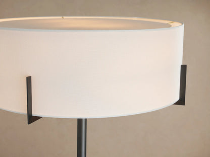 Frederic Floor Lamp with dark bronze pole, white linen drum shade, and black square base with round cream marble detail.