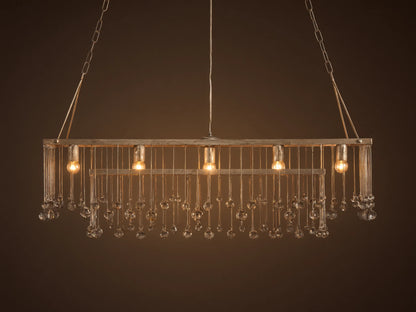 Aubrey Rectangular Chandelier with a silver handcrafted iron frame, hanging Italian glass crystals, and five glowing bulbs.