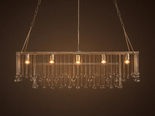 Aubrey Rectangular Chandelier with a silver handcrafted iron frame, hanging Italian glass crystals, and five glowing bulbs.