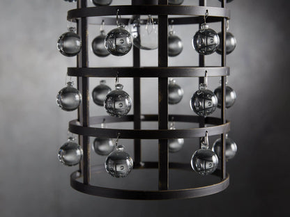 Iron cage pendant with antiqued metallic finish, adorned with Italian crystal spheres, hanging from a chain on a textured wall background.