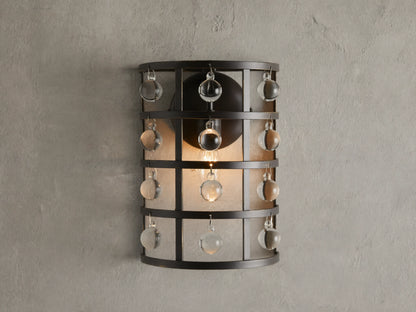 Iron cage sconce with antiqued metallic finish and Italian crystal spheres, mounted on a textured wall, lit from within.