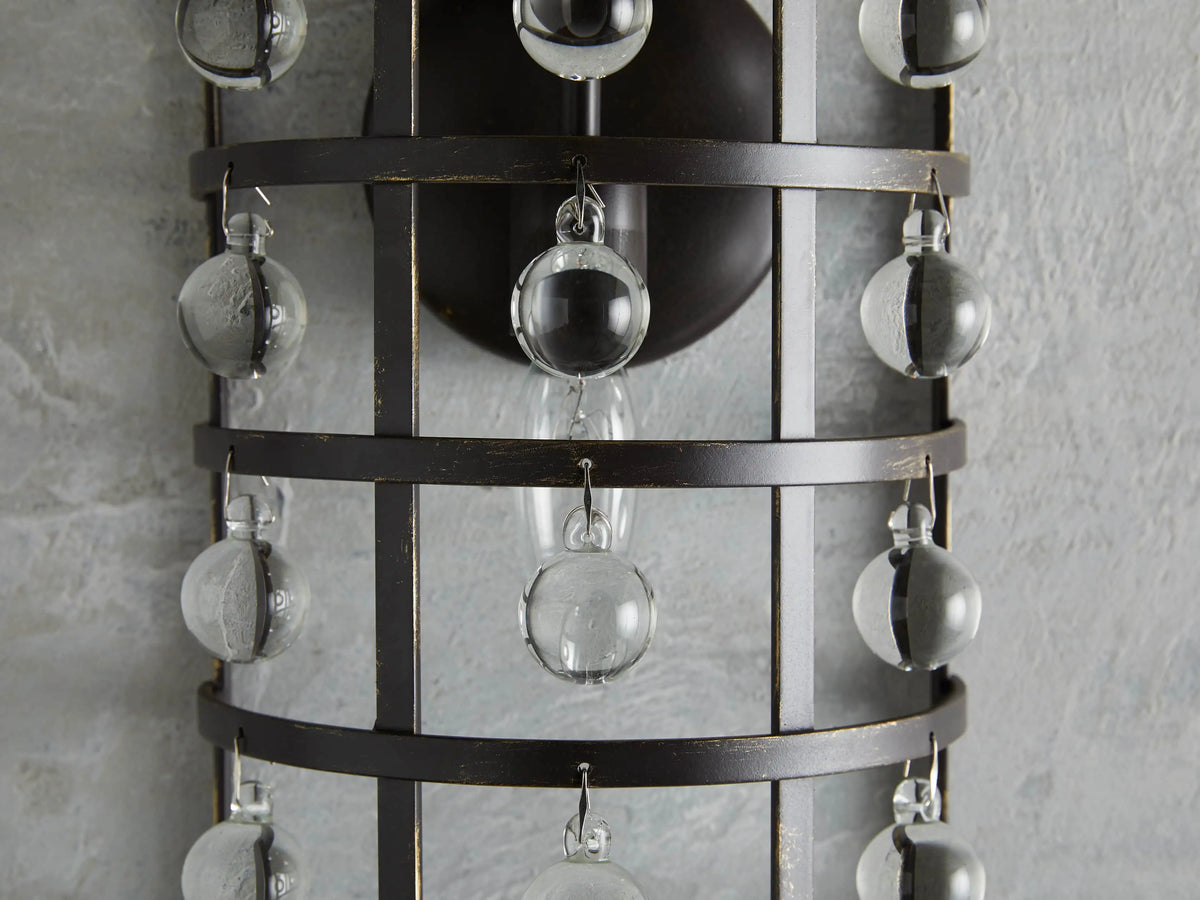 La Cage Sconce with iron cage frame, antiqued metallic finish, and hanging Italian crystal spheres, mounted on wall.