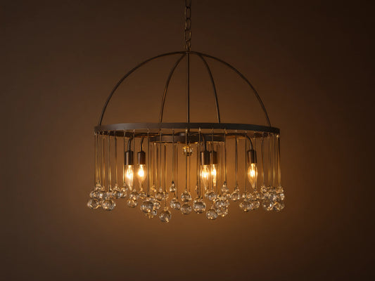 A round chandelier made of solid iron with five exposed bulbs and hanging glass accents, suspended by an iron chain.