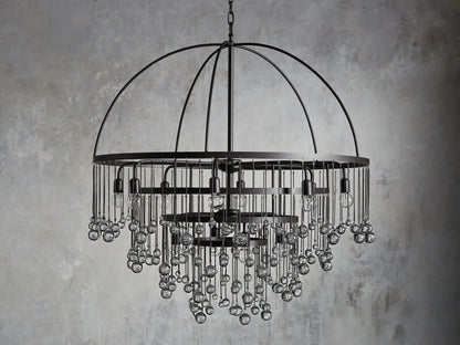 A round chandelier with a dark iron frame, featuring cascading glass orbs and five visible lit bulbs, hanging from a chain.