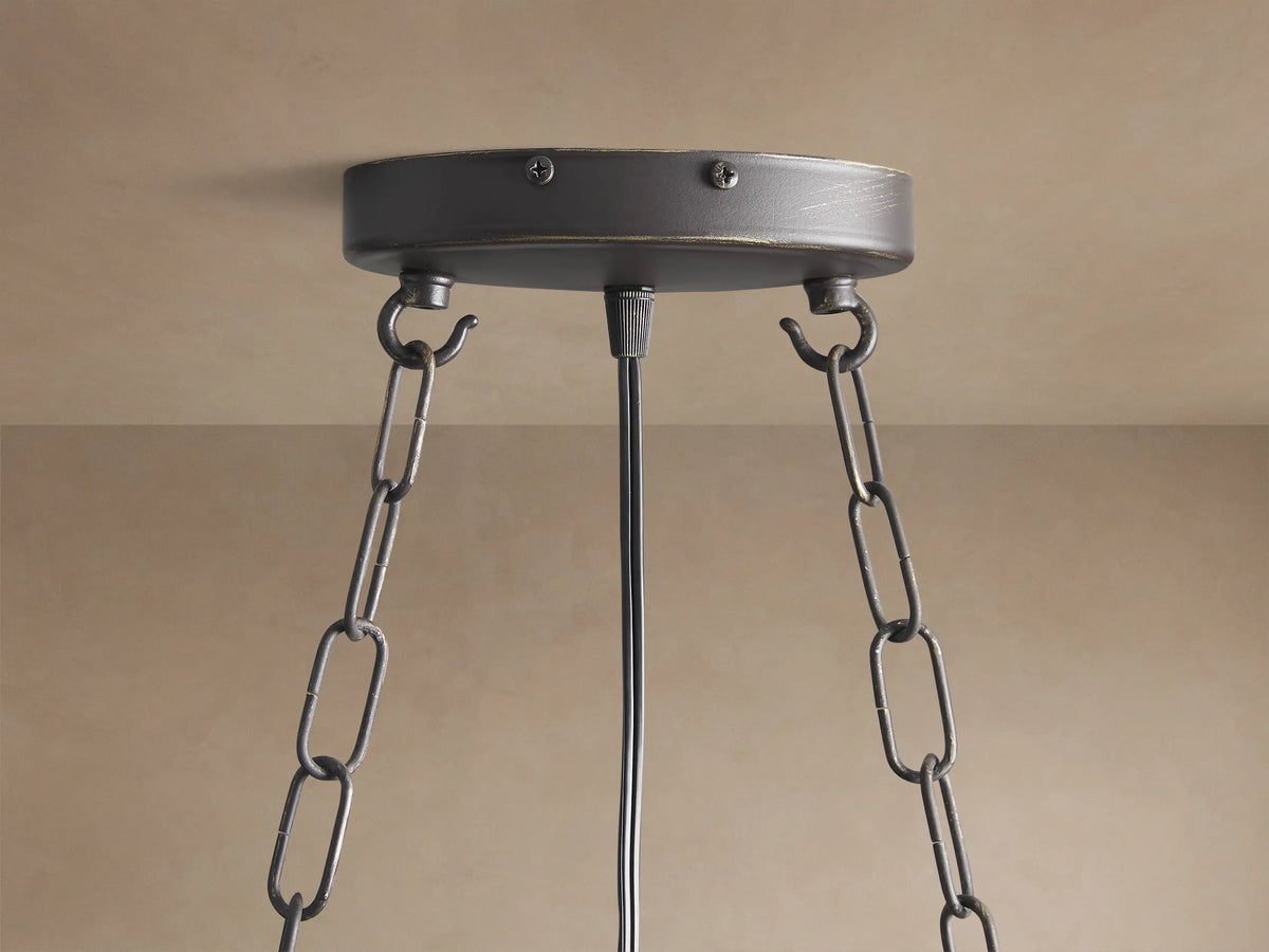 Close-up of Aubrey Rectangular Chandelier: dark iron frame, glowing bulbs, many distressed mercury glass spheres hanging.