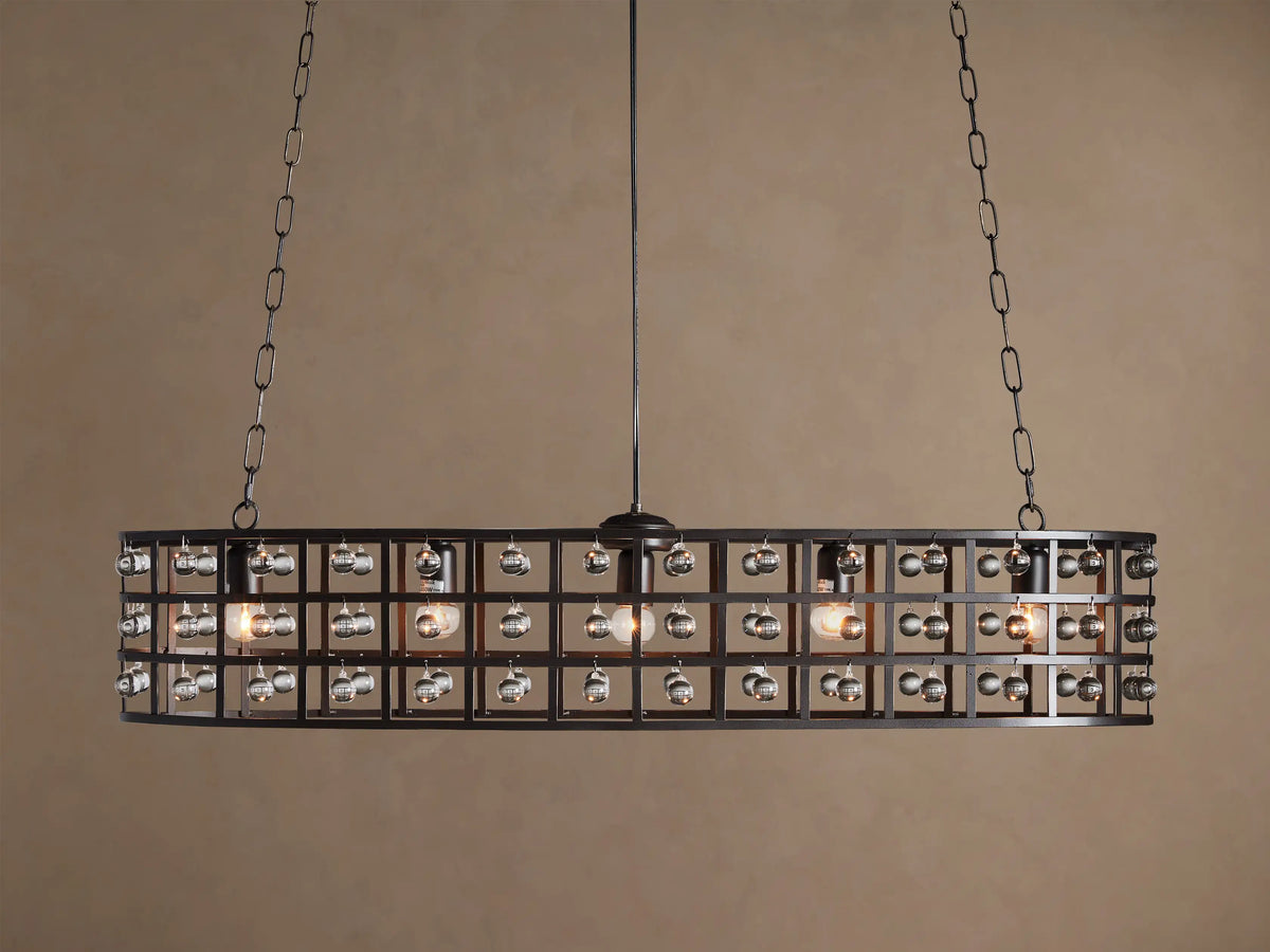La Cage Oval Chandelier: Dark metal cage frame, oval-shaped, adorned with clear crystal spheres and glowing bulbs, suspended by chains.
