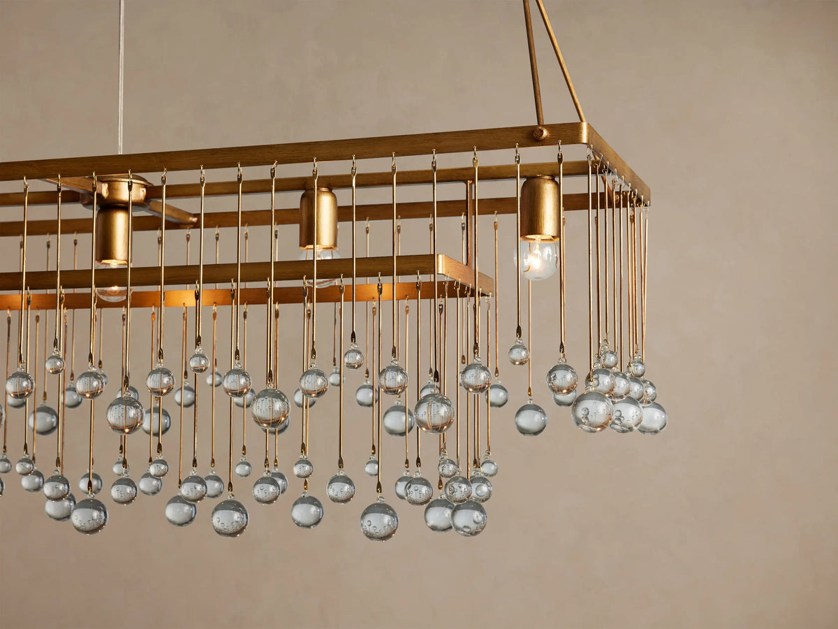 Aubrey Rectangular Chandelier: Rectangular gold-toned chandelier with clear glass spheres hanging at varying lengths, suspended by chains.