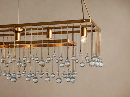 Aubrey Rectangular Chandelier: Rectangular gold-toned chandelier with clear glass spheres hanging at varying lengths, suspended by chains.