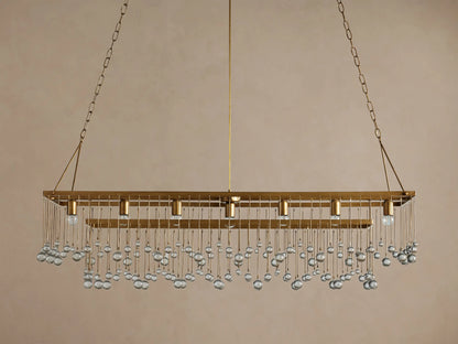 Aubrey Rectangular Chandelier, antique brass finish, adorned with rows of clear glass beads, five bulbs visible, against a wall.