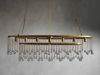 Oval chandelier with gold finish and clear glass droplets, hanging from a double chain. Holds seven bulbs, against a gray background.
