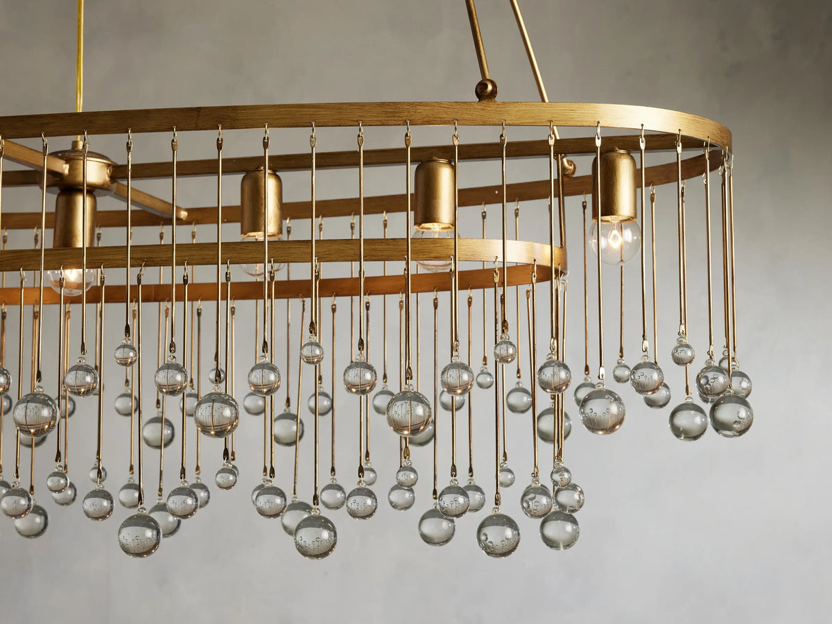 Aubrey Oval Chandelier with a brushed gold finish, featuring seven bulb holders and hanging glass beads, suspended by iron chains.