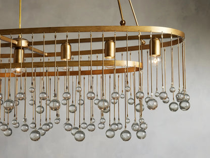 Aubrey Oval Chandelier with a brushed gold finish, featuring seven bulb holders and hanging glass beads, suspended by iron chains.