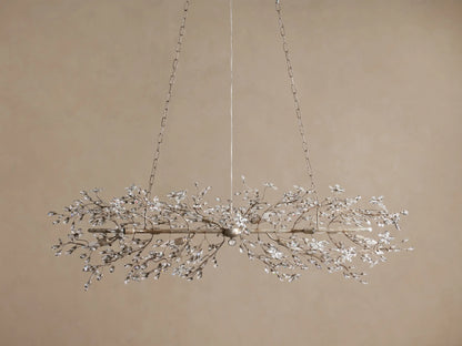 Fiore Linear Chandelier: long, antique silver frame with sparkling clear crystal flower clusters and visible bulbs, suspended by chains.