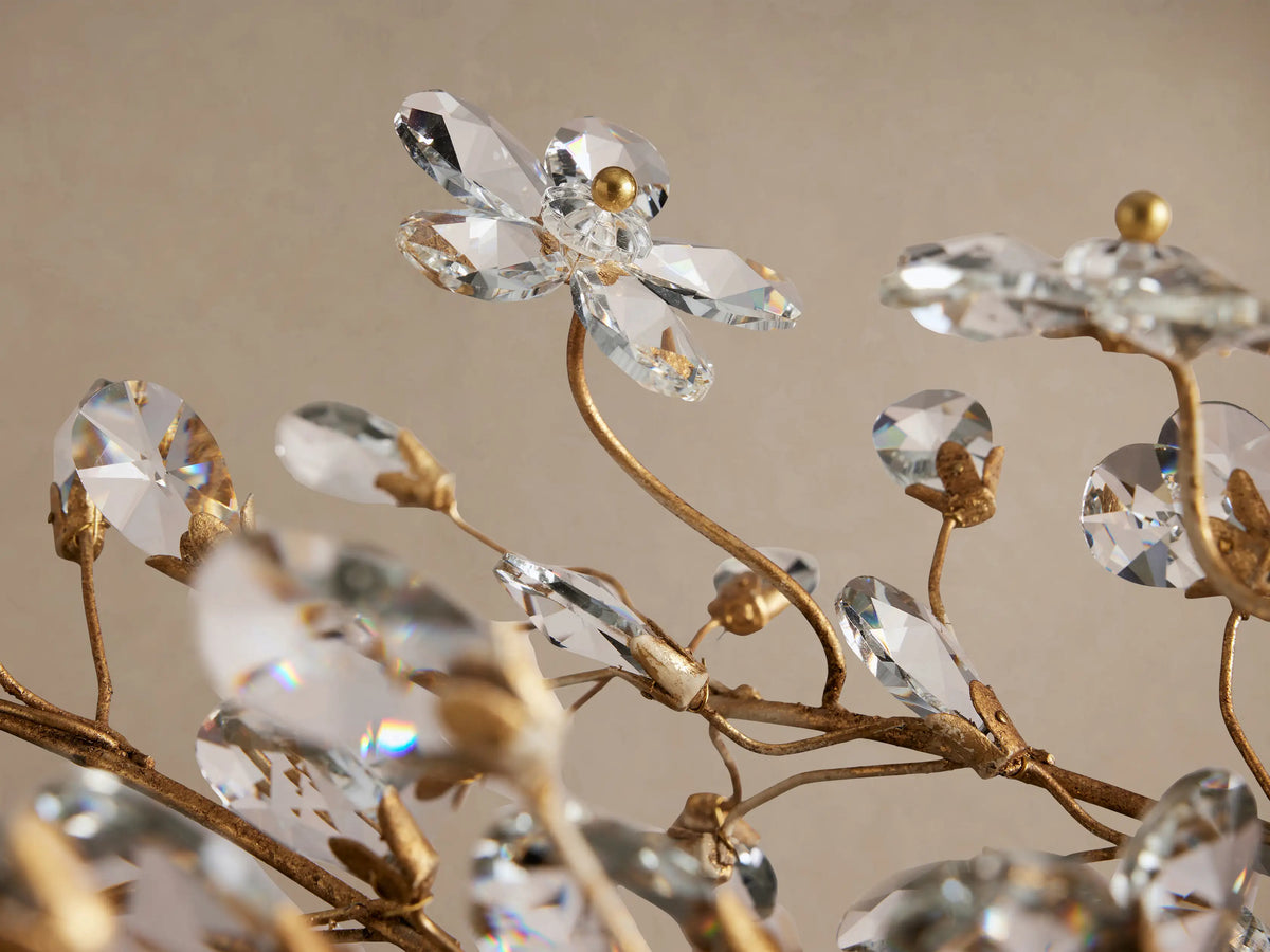Fiore Linear Chandelier: Gold-toned branching metal frame adorned with numerous clear crystal leaves, suspended by chains.