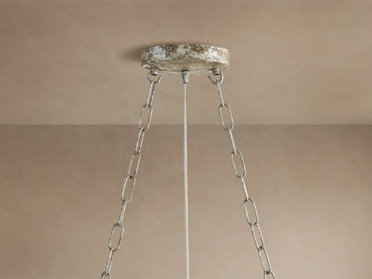 Close-up of Fiore Linear Chandelier with clear crystal flower & faceted leaves on antiqued silver-gold branches against beige.