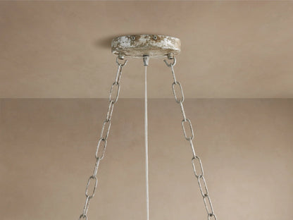 Close-up of Fiore Linear Chandelier with clear crystal flower & faceted leaves on antiqued silver-gold branches against beige.