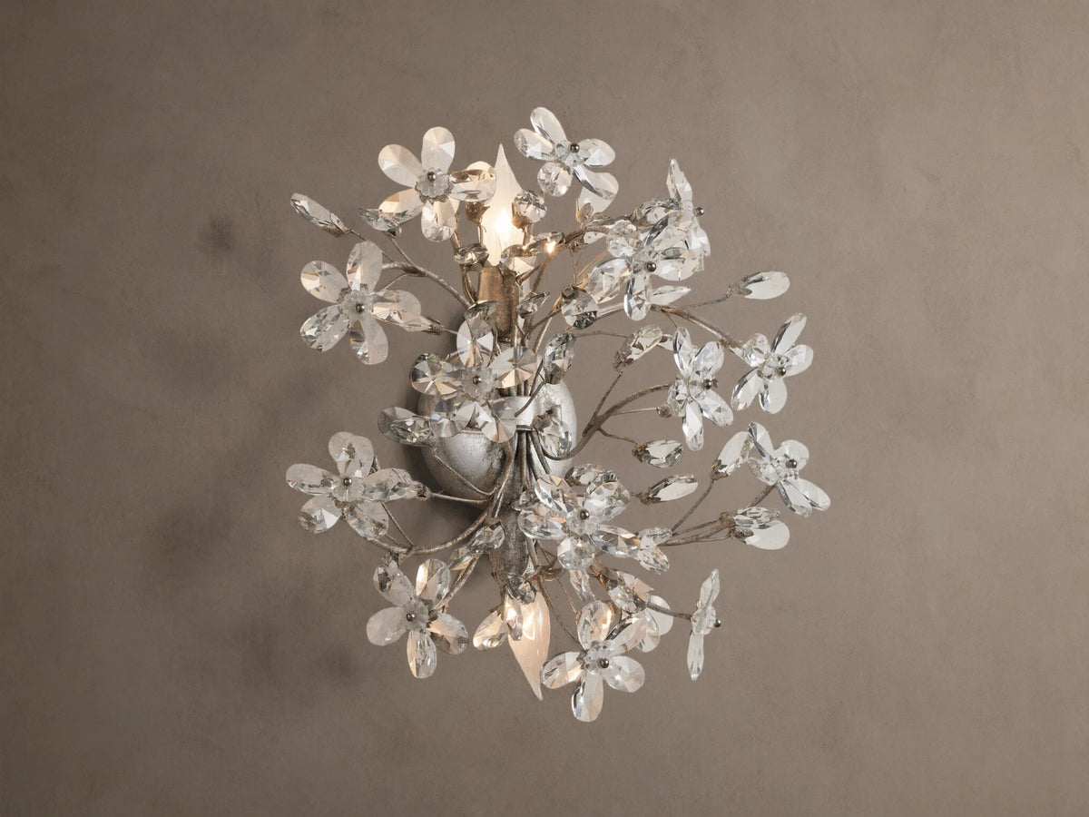 Antiqued silver Fiore Sconce, wall-mounted, featuring numerous clear crystal flowers & buds, with two lit candelabra bulbs.