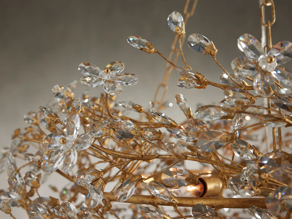 Close-up of Fiore Crown Chandelier: intricate gold branches with sparkling clear crystal flowers & buds. Warm light bulb glow.