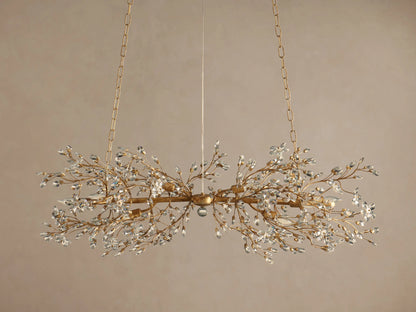 Gold Fiore Linear Chandelier suspended by chains, featuring delicate branches adorned with numerous clear crystal leaves & flowers.