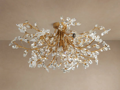 Gold Fiore Flush Mount fixture with branch-like arms, adorned with sparkling clear crystal flowers, on a beige ceiling.