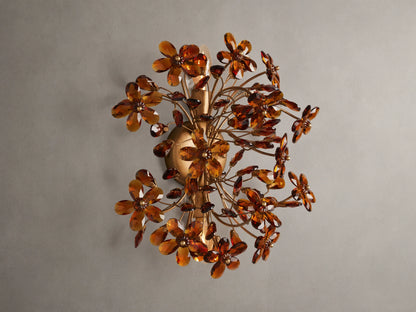Fiore Sconce with a gold antiqued leaf design, featuring amber-colored flower-like structures radiating outward from a central base.