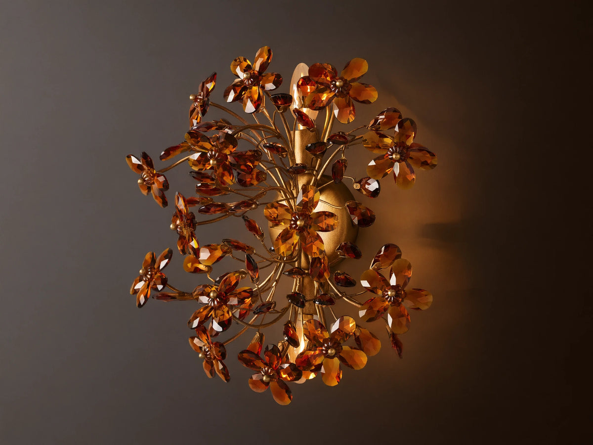 Fiore Sconce with a gold antiqued leaf design, featuring amber-colored flower-like structures radiating outward from a central base.