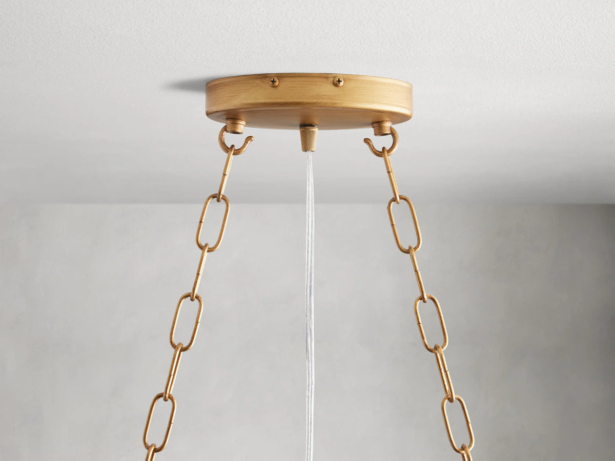 Alt text: Close-up of the Fiore Linear Chandelier featuring hand-applied antique leaf design, with amber-colored crystal accents and gold-finished iron branches.