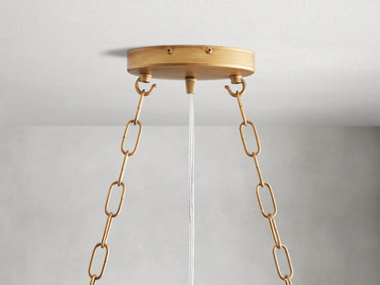 Alt text: Close-up of the Fiore Linear Chandelier featuring hand-applied antique leaf design, with amber-colored crystal accents and gold-finished iron branches.