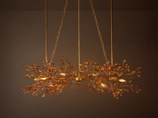 Fiore Linear Chandelier with bronze finish and ornate branching leaf design, suspended by chains against a plain background.