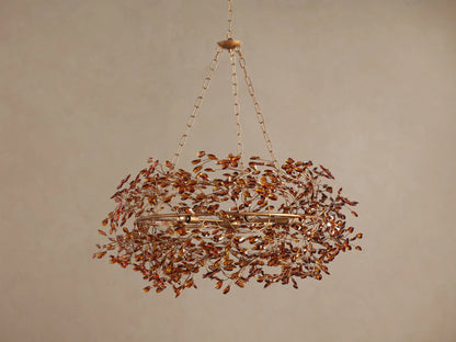 Fiore Crown Chandelier: Gold-finished, circular chandelier adorned with numerous amber crystal leaves, hanging from a chain.