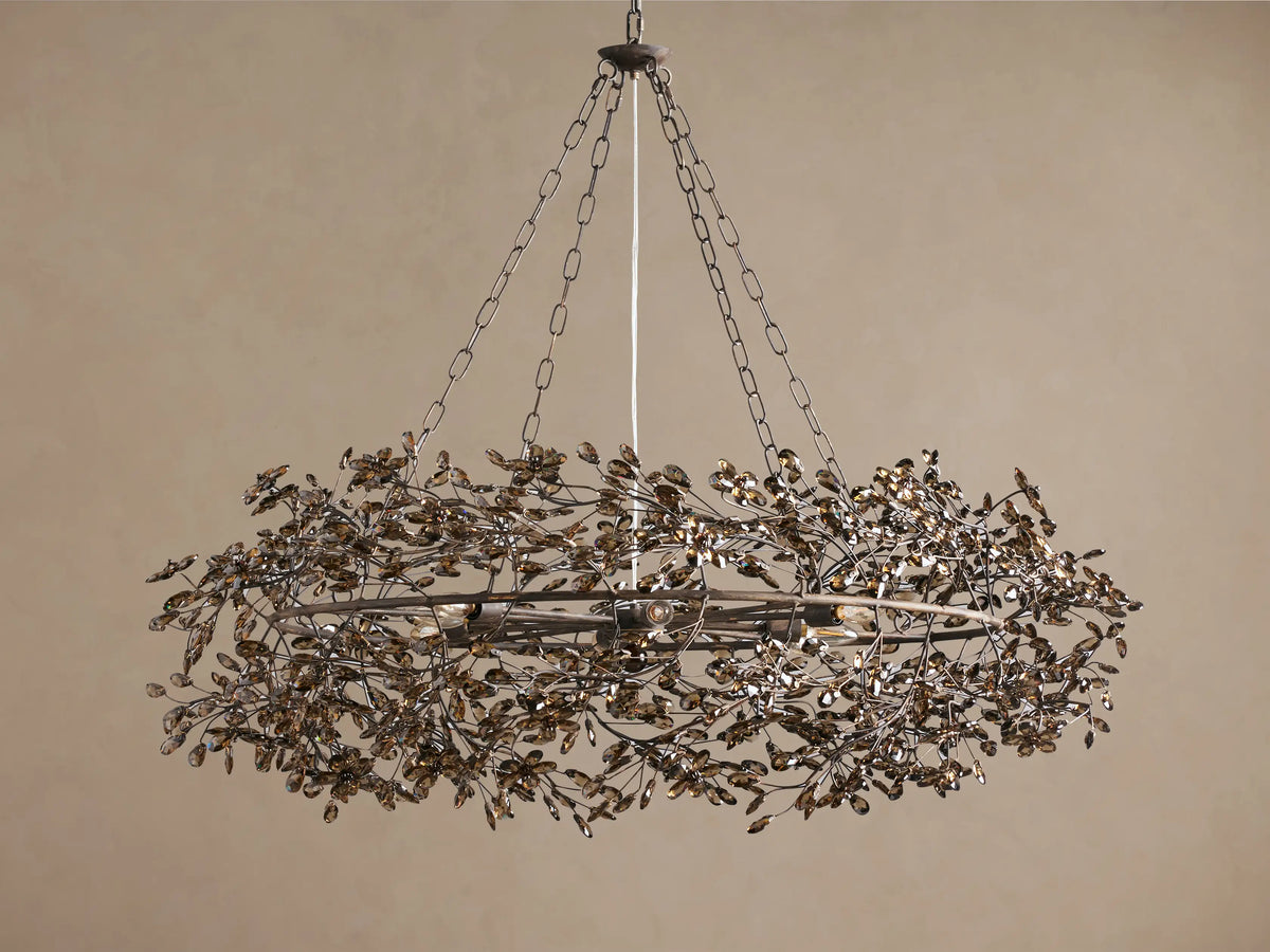 Fiore Crown Chandelier, an antique metal wreath-shaped fixture with many amber leaf-like crystals, hanging from chains.