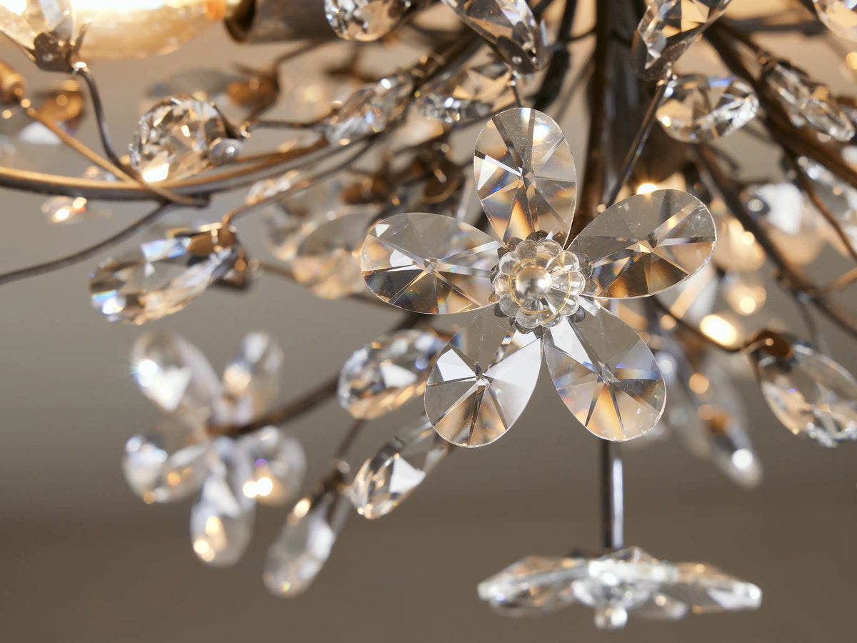 Fiore Crown Chandelier close-up: clear faceted crystal flowers and leaves on a dark metal frame, sparkling with light.