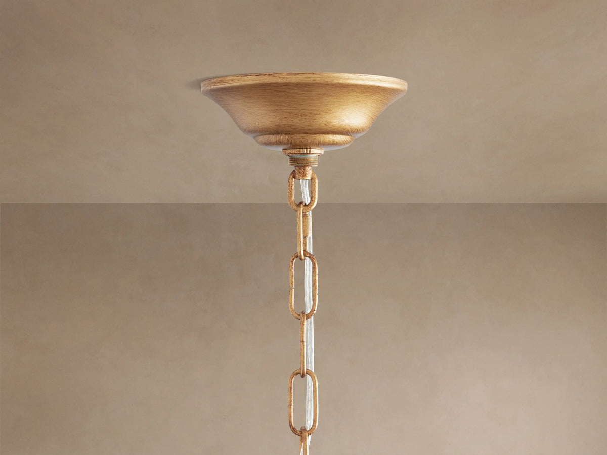 Fiore Crown Chandelier's gold ceiling canopy and chain with clear accents, hanging from a neutral-colored ceiling.