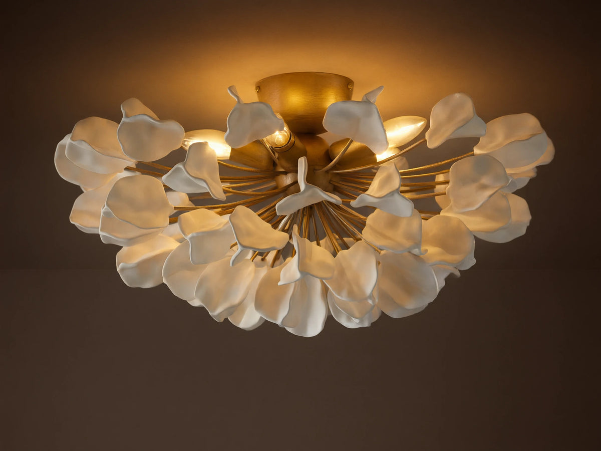 Lunaria Flush Mount with cascading white ceramic leaves and a brass base, lit softly from above, mounted on a ceiling.