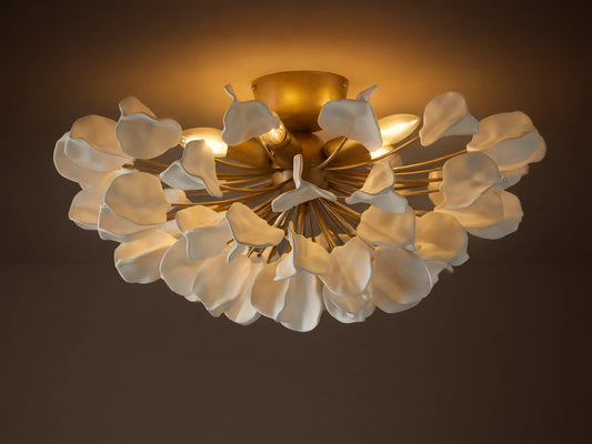 Lunaria Flush Mount with cascading white ceramic leaves and a brass base, lit softly from above, mounted on a ceiling.