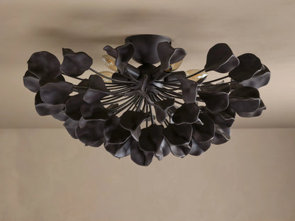 Lunaria Flush Mount with dark iron finish and ceramic leaves, illuminated from behind, mounted on beige ceiling.