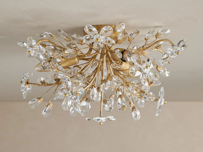 Fiore Flush Mount, an elegant gold light fixture with numerous clear crystal flower and teardrop shapes sparkling on a ceiling.