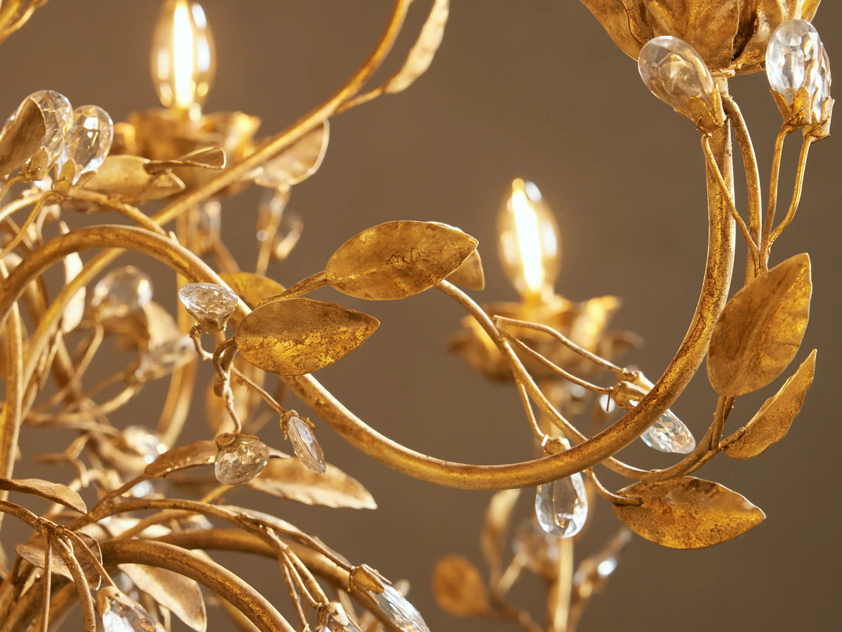 Close-up of golden Nicoletta Round Chandelier with intricate leaf details, clear crystal accents, and glowing bulbs.