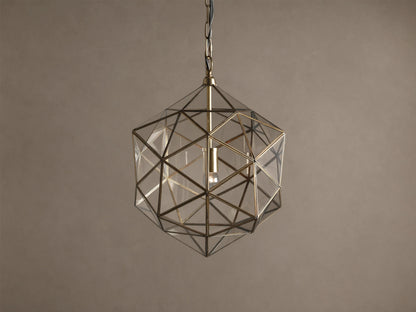 Eliana Lantern Pendant: Geometric brass and clear glass lantern hanging from a black chain, with a light bulb inside.
