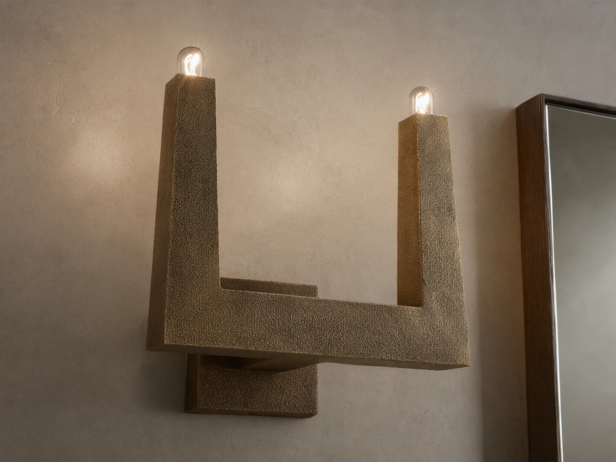 Front view of textured bronze U-shaped wall sconce with two glowing bulbs.