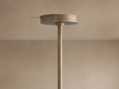 Close-up of Emmet Round Chandelier, showing its textured antiqued brass finish, sturdy round frame, vertical arms with glowing bulbs.