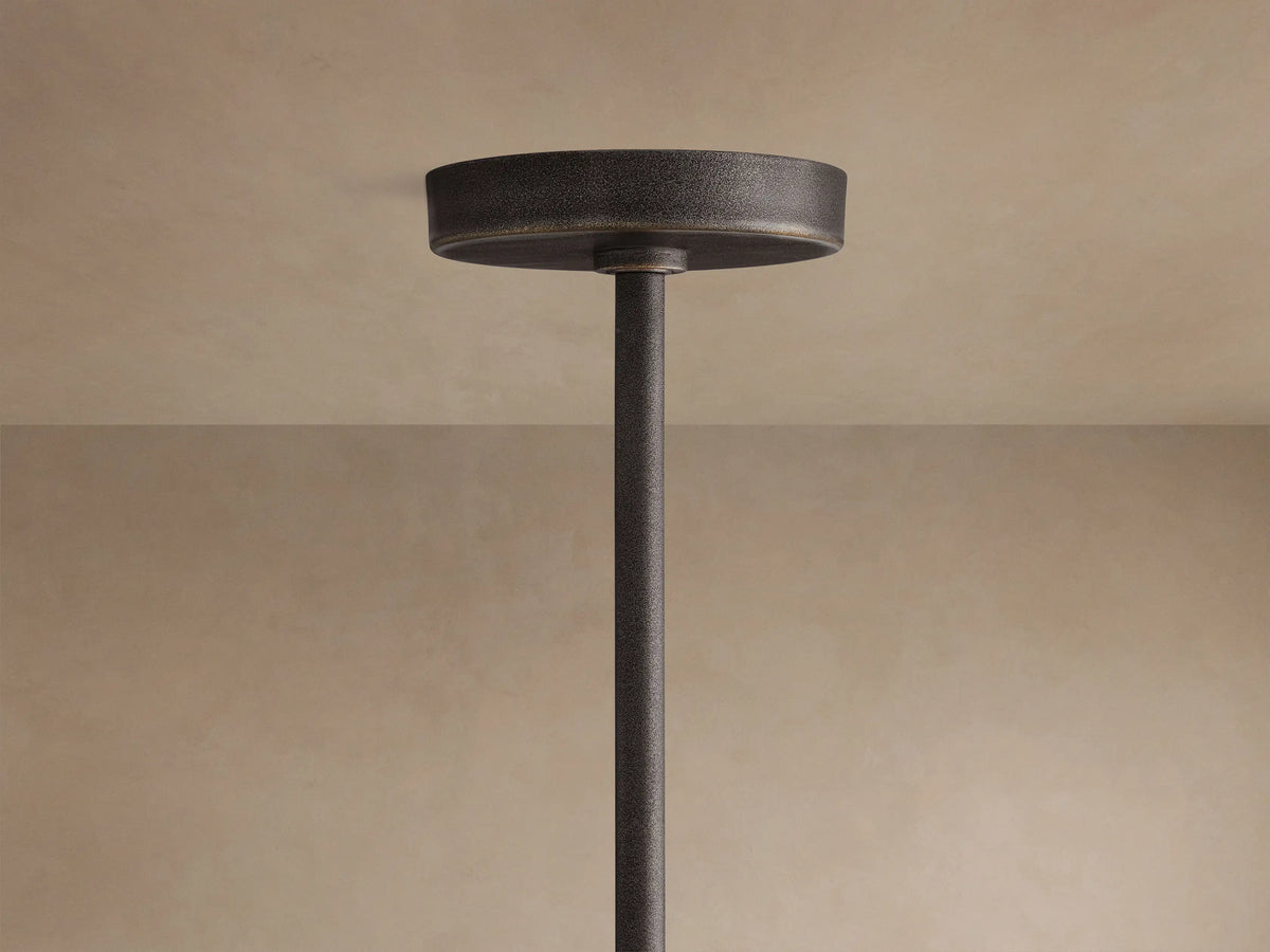 Close-up, angled view of Emmet Round Chandelier with dark antiqued brass finish, round frame, and glowing filament bulbs.