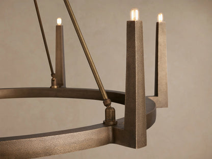 Antiqued brass Emmet Round Chandelier with a circular base, 6 tapered arms holding clear bulbs, suspended by rods.