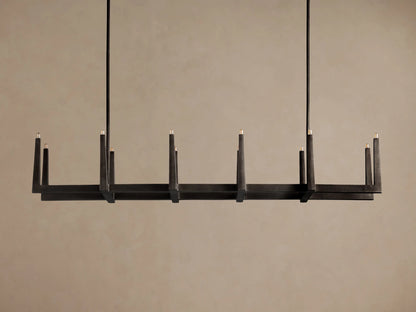 Emmet Linear Chandelier, dark antiqued textural brass, rectangular frame, 8 glowing candle-like lights on dark background.