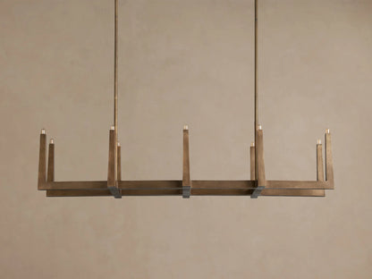 Emmet Linear Chandelier with antiqued brass finish, featuring a rectangular frame and multiple illuminated candle-like bulbs.