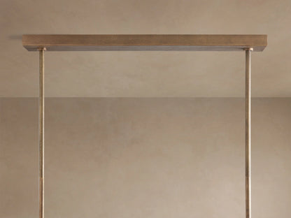 Close-up of Emmet Linear Chandelier. Antiqued brass, sand-casted frame with vertical arms and illuminated bulbs.