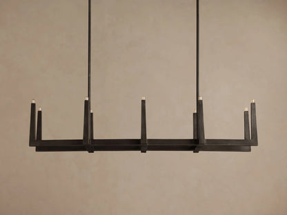 Emmet Linear Chandelier, dark antiqued brass linear fixture hung horizontally, showcasing ten lit candle-style bulbs.