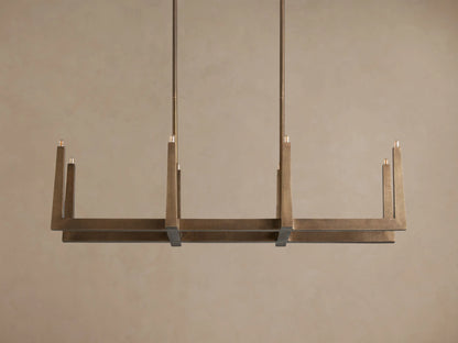 Emmet Linear Chandelier: Textured antiqued brass, linear rectangular frame with illuminated upright bulbs, suspended from rods.