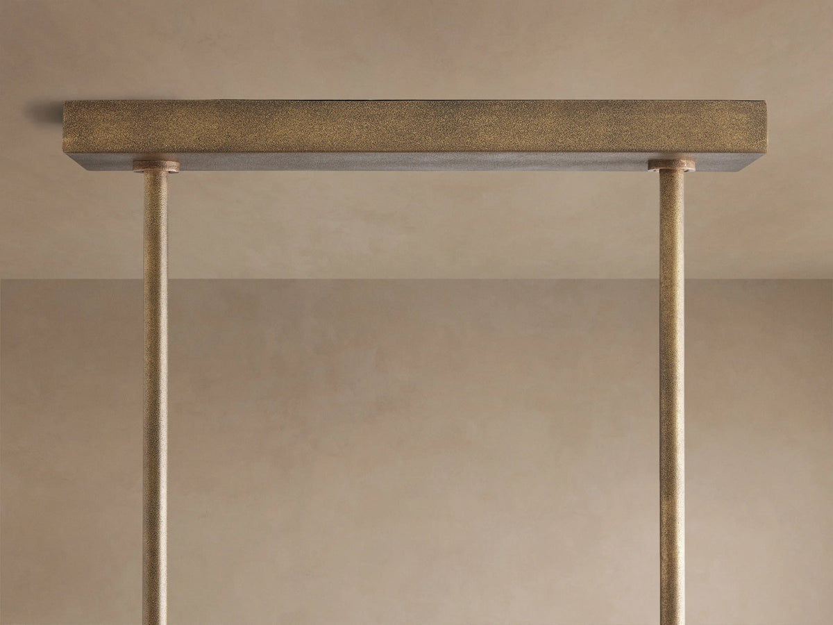 Close-up Emmet Linear Chandelier: textured antiqued bronze linear frame with upright arms, glowing LED filament bulbs.