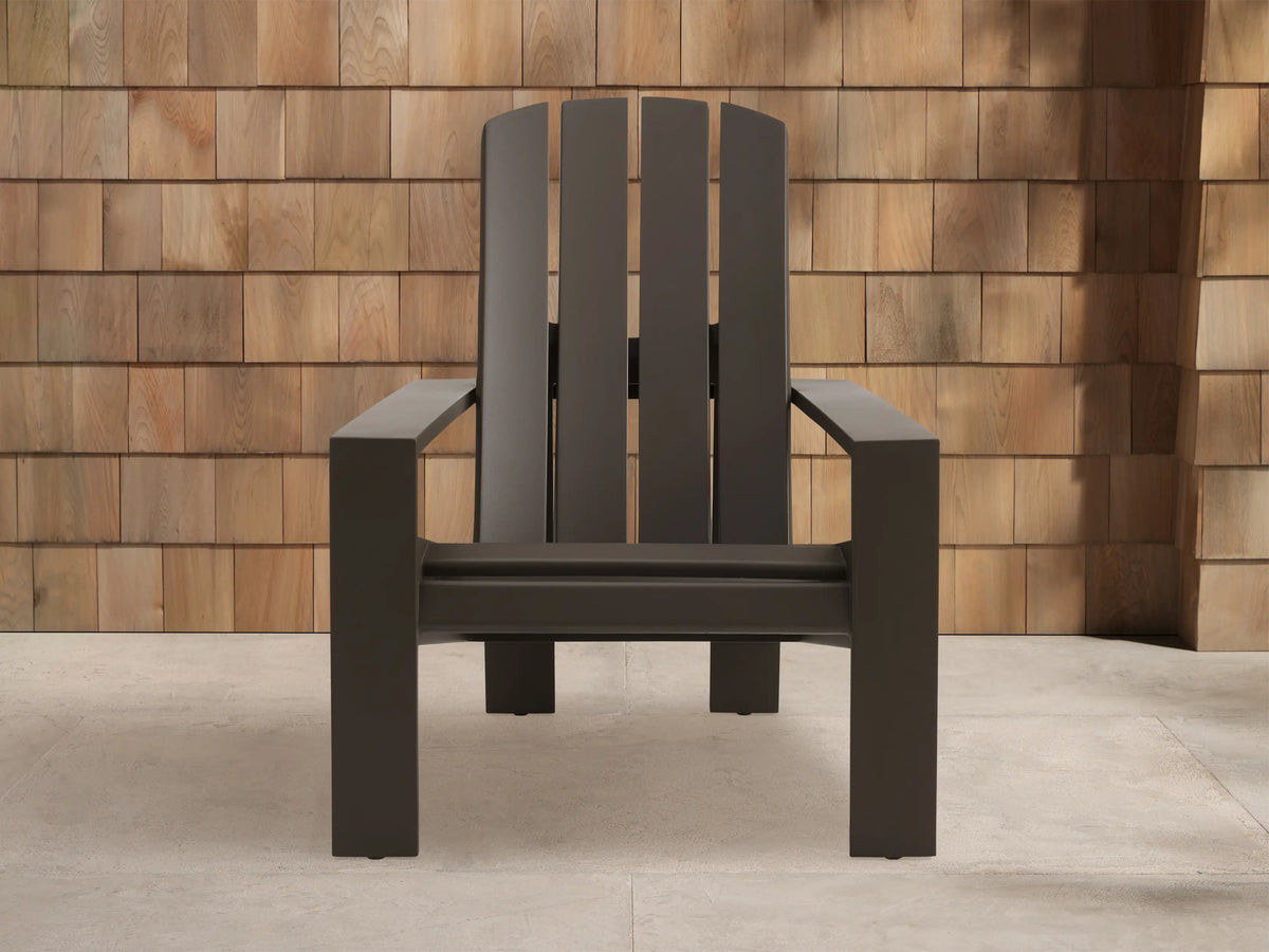 Powder-coated dark bronze Adirondack outdoor aluminum lounge chair, angled against a wooden shingle wall on light pavement.